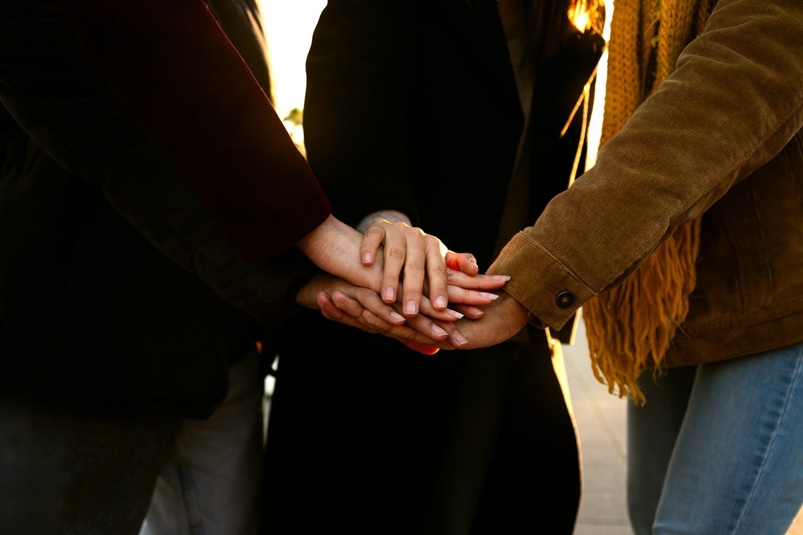 Close up of unrecognisable people stacking hands as a symbol of unity, community and friendship.